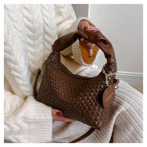 Détail d'un sac à main en cuir marron tressé main avec poignée plissée et étiquette