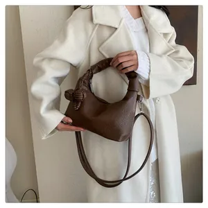 Detail of soft brown leather tote with hand-woven knot handle and adjustable strap