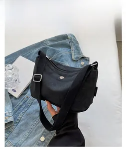 Detail of black canvas crossbody bag with adjustable strap and silver metal buckle
