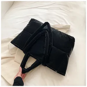 Vue de dessus d'un sac cabas noir matelassé sur une literie douce avec détails soignés