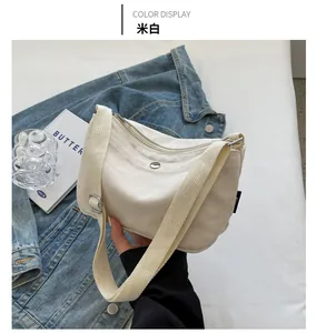 Close-up of beige canvas crossbody bag featuring adjustable strap and smooth metal button