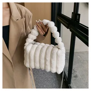 Close-up of white plush handbag with vertical quilted texture and fluffy bead handle