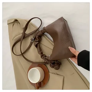Detail of dark brown lychee texture leather handbag with elegant knot tassel charm
