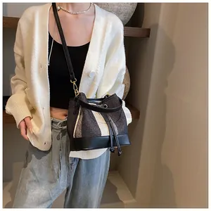 Detail of striped bucket bag featuring woven texture and adjustable shoulder strap