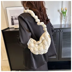 Detalle de bolso medialuna acolchado blanco con asa fruncida en el hombro de modelo