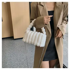 Detail view of white plush handbag with textured fur, bubble handle and silver chain strap