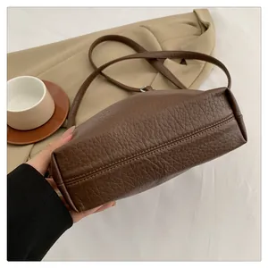 Detail showing high-quality lychee pattern brown leather texture and reinforced stitching