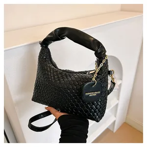 Détail d'un sac à main tissé noir avec poignées pelucheuses et étiquette à chaîne dorée