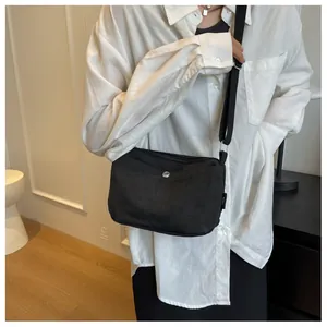 Detail of minimalist black canvas crossbody bag featuring adjustable strap and metal snap