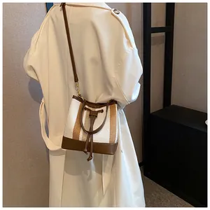 Detail of color-block canvas bucket bag with leather trim and drawstring closure