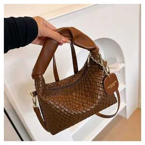 Détail d'un sac à main tissé à la main en cuir marron avec fermeture éclair et étiquette