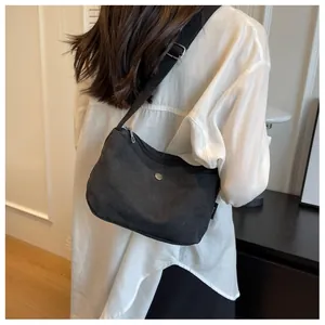 Detail of the black canvas crossbody bag showing the thick strap and silver metal hardware