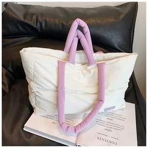 Gros plan du sac cabas matelassé crème avec poignées lilas posé sur un magazine