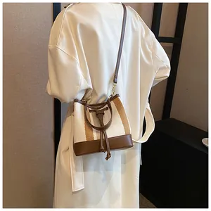 Detail of contrast stripe bucket bag with drawstring closure and leather shoulder strap