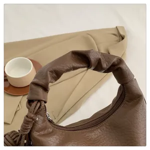 Detail of dark brown faux leather handbag featuring a stylish scrunchie handle design