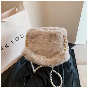 Detail of soft beige faux fur handbag featuring elegant pearl strap and gold hardware