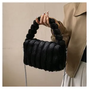 Detailed view of black faux fur handbag with vertical quilting and silver chain strap