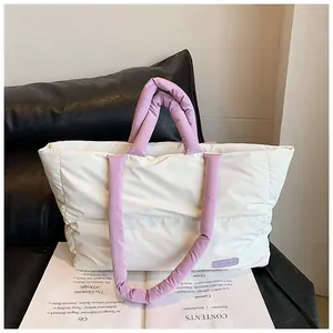 Détail du sac cabas matelassé crème et violet posé sur un magazine d'art moderne