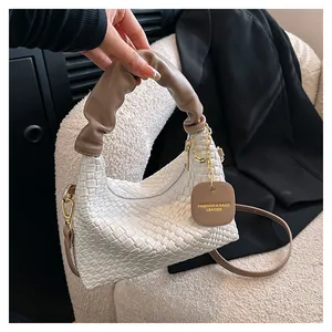 Détail de la texture tressée blanche avec poignée marron et chaîne dorée sur sac à main
