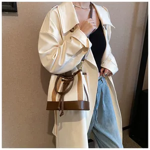 Detail of striped canvas bucket bag with brown leather trim and adjustable shoulder strap
