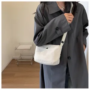 Detailed lifestyle shot of white canvas crossbody bag with adjustable strap and metal buckle