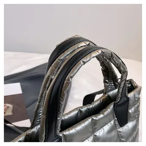 Dettaglio della borsa trapuntata argento metallizzato con manici in pelle nera e tessuto morbido