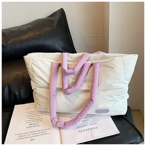 Détail d'un sac cabas matelassé ivoire avec des poignées violettes et étiquette mode