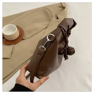 Detail of coffee brown pebble leather shoulder bag featuring unique woven knot accents