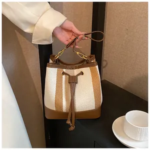 Close-up of vintage striped bucket bag with brown leather trim and drawstring closure