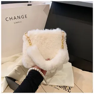 Detail of white faux fur crossbody bag with gold chain and elegant pearl strap