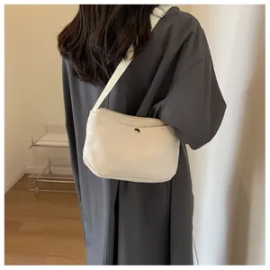 Detailed side view of off-white canvas crescent bag with silver buckle and wide strap