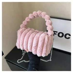 Detail of pink plush handbag with spherical fur handle and silver chain strap