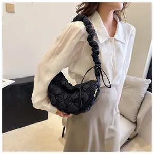 Detalle del bolso medialuna negro acolchado con textura de nube y correa fruncida de moda