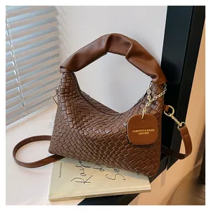 Détail d'un sac cabas tressé marron avec accessoires dorés et poignée plissée