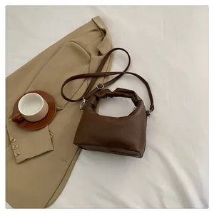 Detail view of brown lychee grain leather mini bag with elegant ruched handle and silver clips