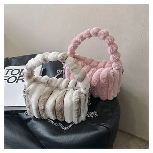 Detail of plush crossbody bags with faux fur stripes, chain straps and pom-pom handles