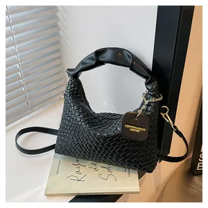 Détail du sac à main tissé noir avec poignée plissée et chaîne en métal doré