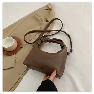 Detail of dark brown faux leather bag with unique pleated cloud handle and long strap
