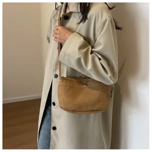 Close-up of minimalist khaki canvas crossbody bag with metal button pocket detail
