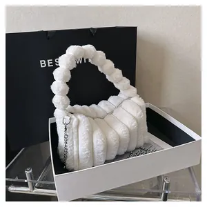 Close-up of plush white handbag with pom-pom handle, chain strap, and elegant gift box
