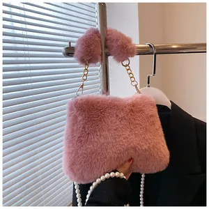 Detail of pink faux fur crossbody bag with golden chain and elegant pearl strap accessories