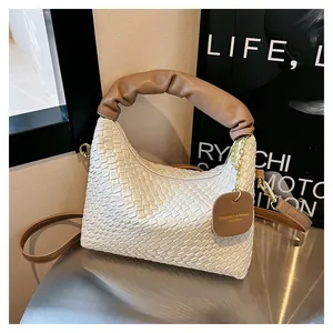 Détail du sac à main tissé main blanc cassé avec poignée marron et chaîne dorée