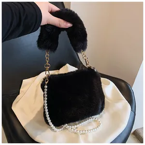 Close-up of black faux fur handbag featuring gold metal buckles and white pearl chain strap