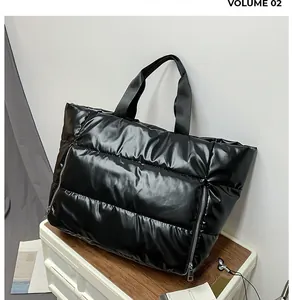 Κοντινό πλάνο μαύρης καπιτονέ τσάντας με γυαλιστερή υφή και διακοσμητικά φερμουάρ