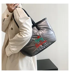 Sac fourre-tout argenté matelassé avec broderie Merry Christmas porté par un mannequin