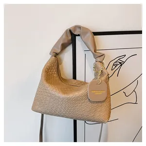 Détail du sac à épaule en cuir tressé kaki avec chaîne dorée et étiquette de mode