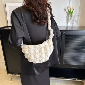 Bolso nube acolchado blanco con correas plisadas en un entorno interior minimalista