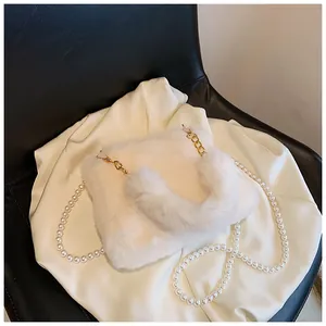 Detail of white faux fur handbag with elegant gold chain and luxury pearl strap