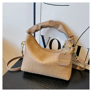 Détail de la texture tissée main, poignée plissée et finitions dorées sur ce sac