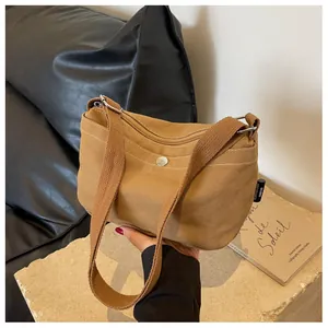 Detail showing brown canvas texture, white stitching and metal magnetic closure of the bag